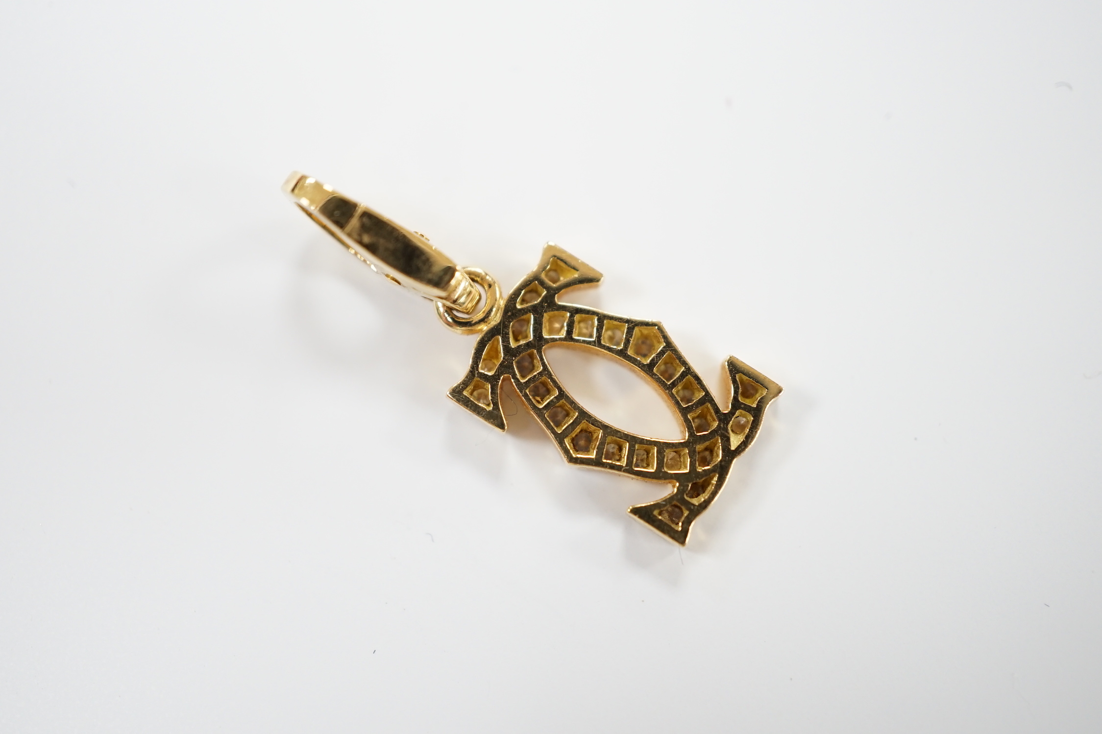 A modern Cartier 750 yellow metal and diamond chip set double C drop pendant, signed and numbered NE6304, overall 25mm, gross weight 2.6 grams, with Cartier box.